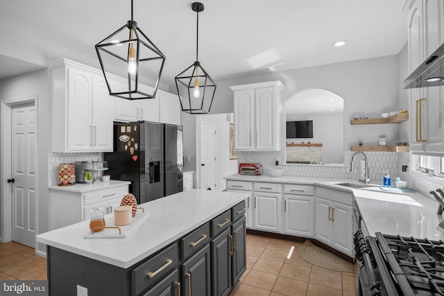 kitchen with a sink, stainless steel fridge with ice dispenser, white cabinets, arched walkways, and tasteful backsplash