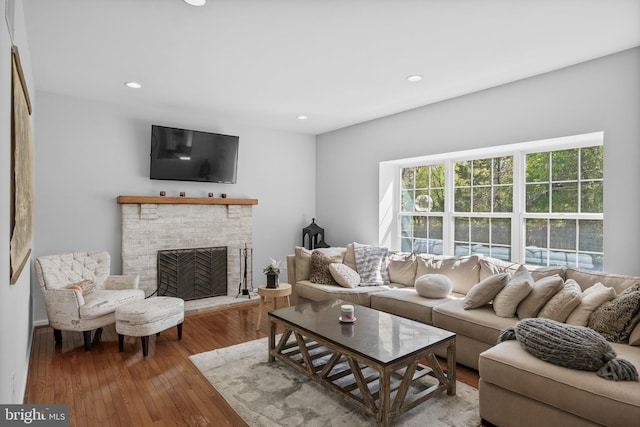 living area featuring a brick fireplace, wood-type flooring, and recessed lighting