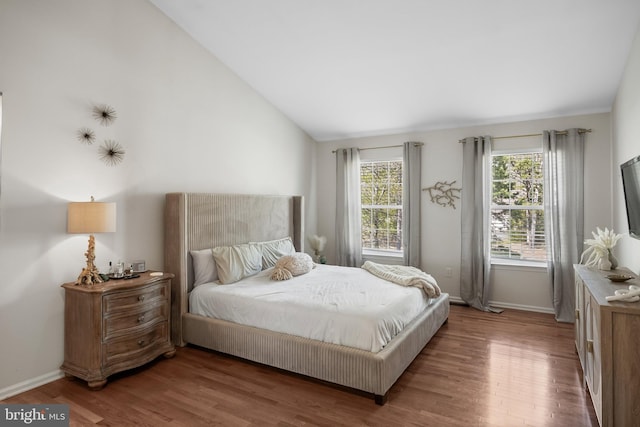 bedroom with baseboards, lofted ceiling, and wood finished floors