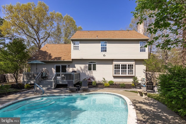rear view of property featuring a chimney, a wooden deck, and a fenced in pool