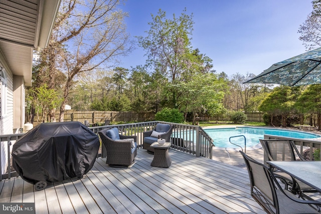 deck featuring a fenced backyard, a fenced in pool, and grilling area