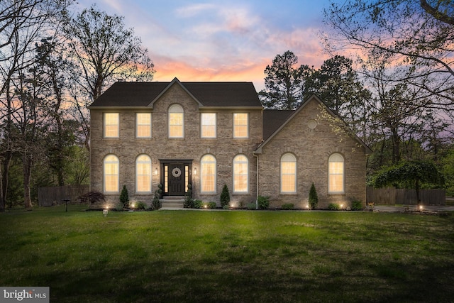 view of front of home featuring a yard, brick siding, and fence