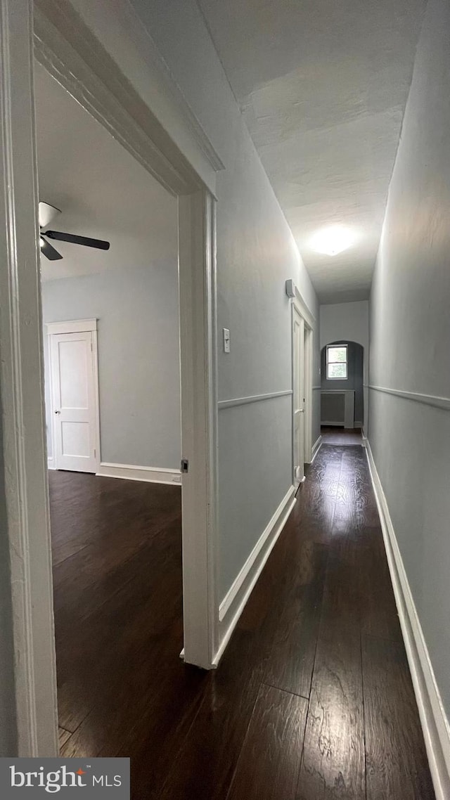 hallway featuring hardwood / wood-style flooring and baseboards