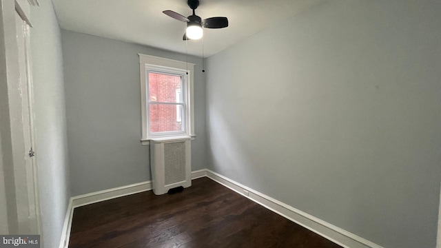 empty room featuring ceiling fan, baseboards, and dark wood finished floors