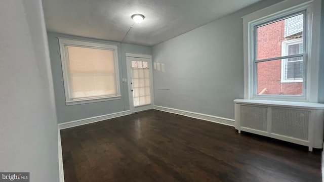 interior space featuring baseboards, radiator, and dark wood finished floors