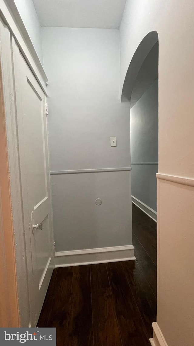 unfurnished room with wood-type flooring, arched walkways, and baseboards