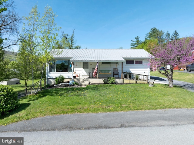 view of front facade featuring covered porch, metal roof, and a front yard