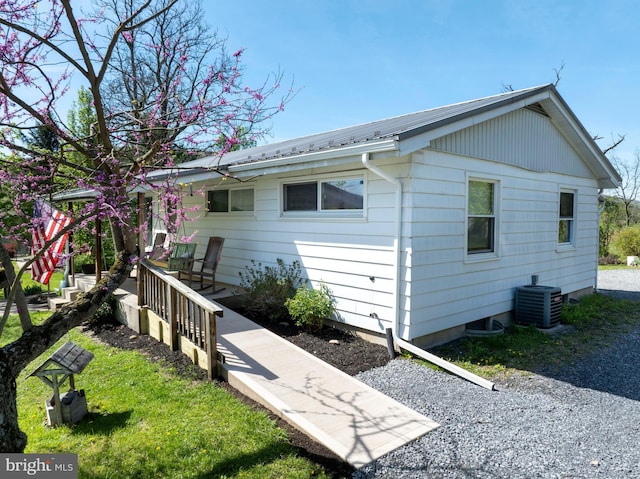 back of house featuring metal roof and central AC