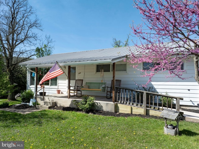 view of front facade with a front lawn, a porch, and metal roof