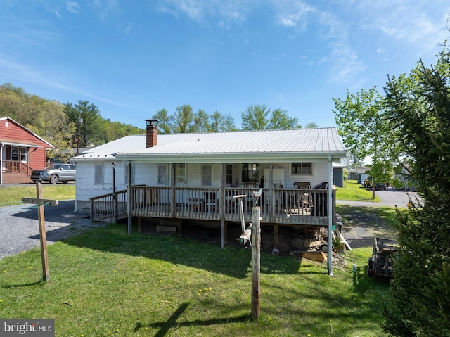 view of front of home with metal roof, a front yard, a chimney, and a porch
