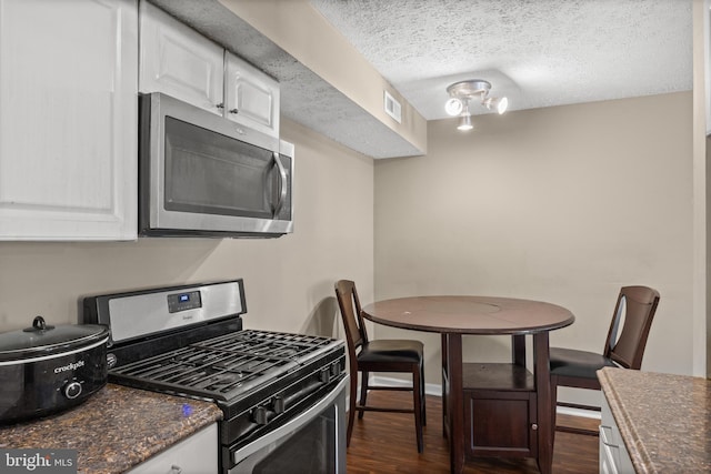 kitchen featuring stainless steel appliances, dark wood-style flooring, white cabinetry, and a textured ceiling