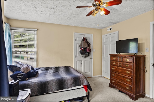 bedroom with light colored carpet, a textured ceiling, a ceiling fan, baseboards, and a closet