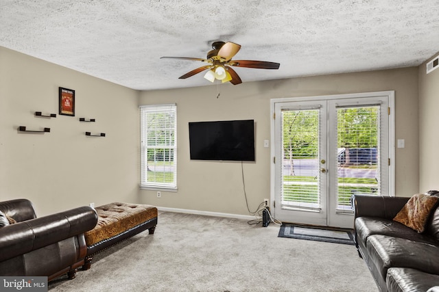 living room featuring french doors, plenty of natural light, a ceiling fan, carpet floors, and a textured ceiling