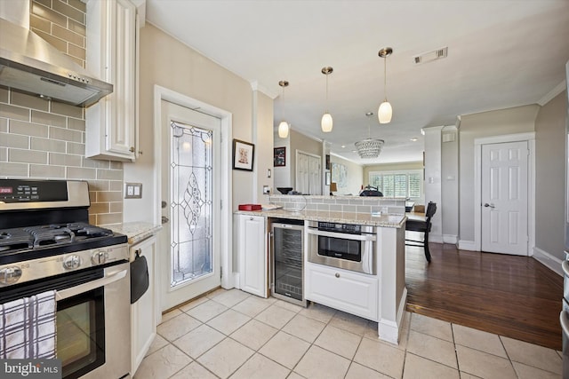 2935 S 13th St, Philadelphia, PA 19148 - kitchen featuring stainless steel appliances, wall chimney range hood, beverage cooler, a peninsula, and crown molding