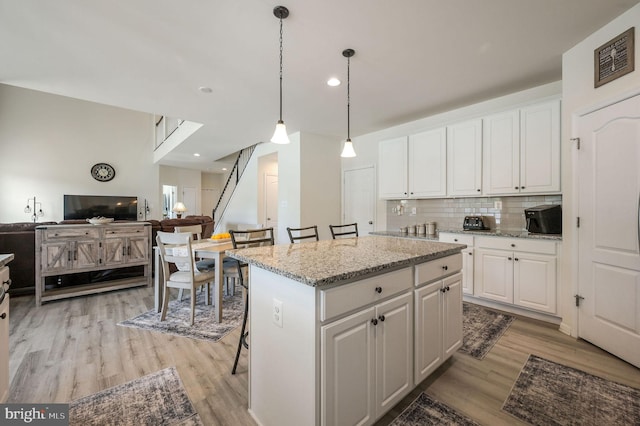 kitchen with light wood-style flooring, tasteful backsplash, visible vents, and white cabinets