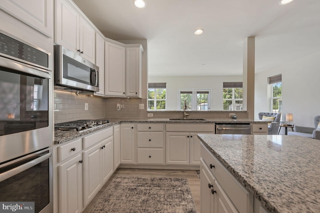 kitchen with a sink, stainless steel appliances, light wood-type flooring, recessed lighting, and white cabinetry