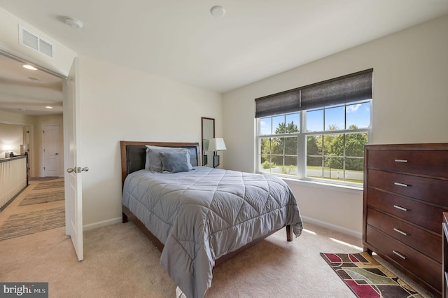 bedroom with baseboards, visible vents, and light colored carpet