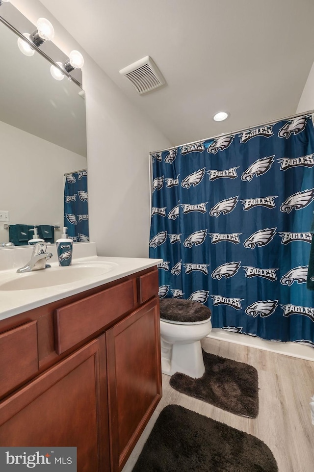 bathroom featuring a shower with curtain, toilet, visible vents, vanity, and wood finished floors