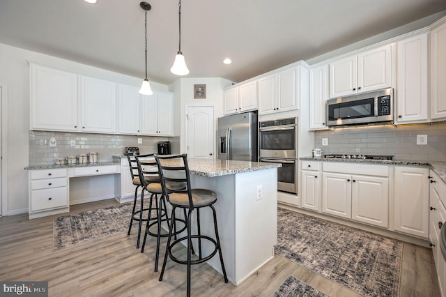 kitchen with light wood-style floors, backsplash, white cabinets, and appliances with stainless steel finishes