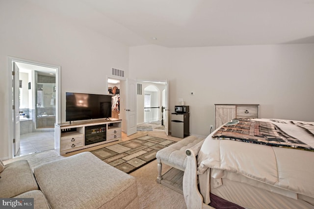 bedroom with multiple windows, ensuite bath, visible vents, and high vaulted ceiling