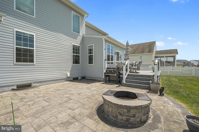 view of patio featuring grilling area, a wooden deck, a fire pit, and fence
