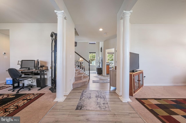 entrance foyer featuring stairway, light wood-style flooring, baseboards, and decorative columns