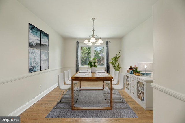 dining space with a chandelier, light wood-type flooring, and baseboards