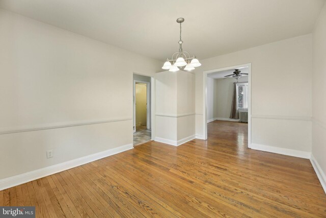 unfurnished dining area with a chandelier, hardwood / wood-style floors, baseboards, and radiator heating unit