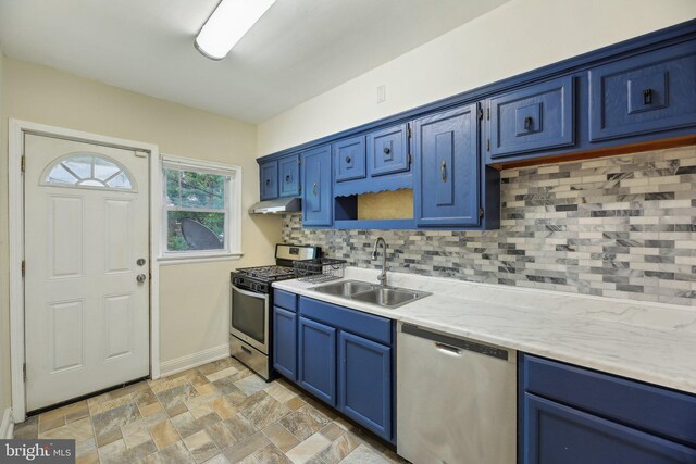 kitchen featuring stainless steel appliances, a sink, blue cabinetry, and tasteful backsplash