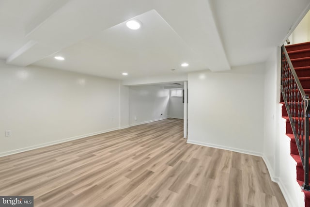 finished below grade area with stairway, light wood-style flooring, baseboards, and recessed lighting