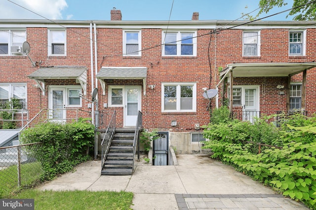 multi unit property with a chimney, brick siding, and fence