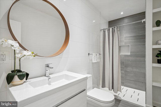 bathroom with vanity, toilet, tile walls, and a shower stall