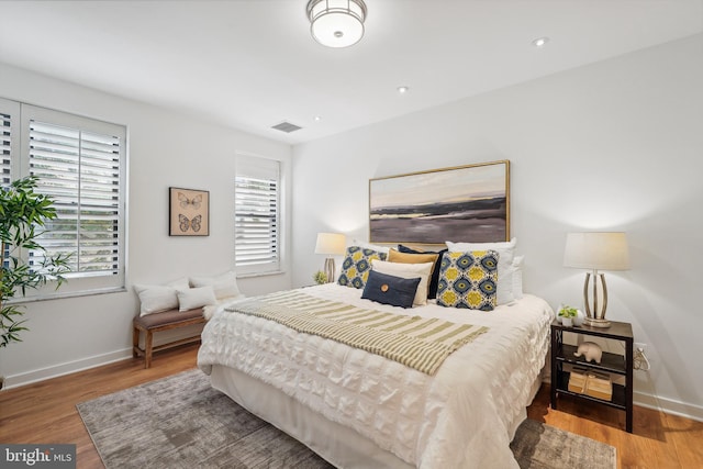 bedroom with baseboards, visible vents, and wood finished floors