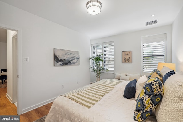 bedroom featuring baseboards, visible vents, and wood finished floors