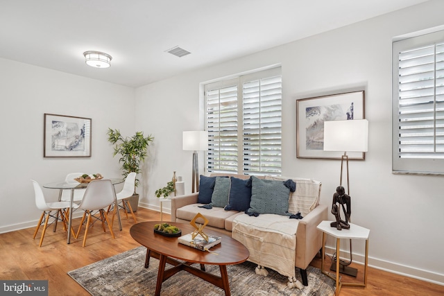 living area featuring baseboards, visible vents, and wood finished floors