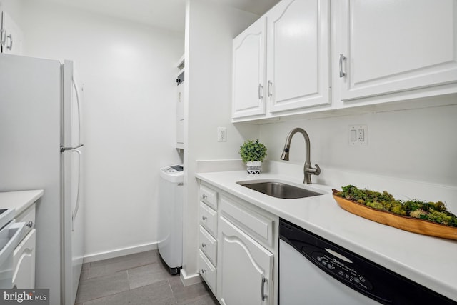 kitchen with light countertops, a sink, white cabinets, baseboards, and dishwasher