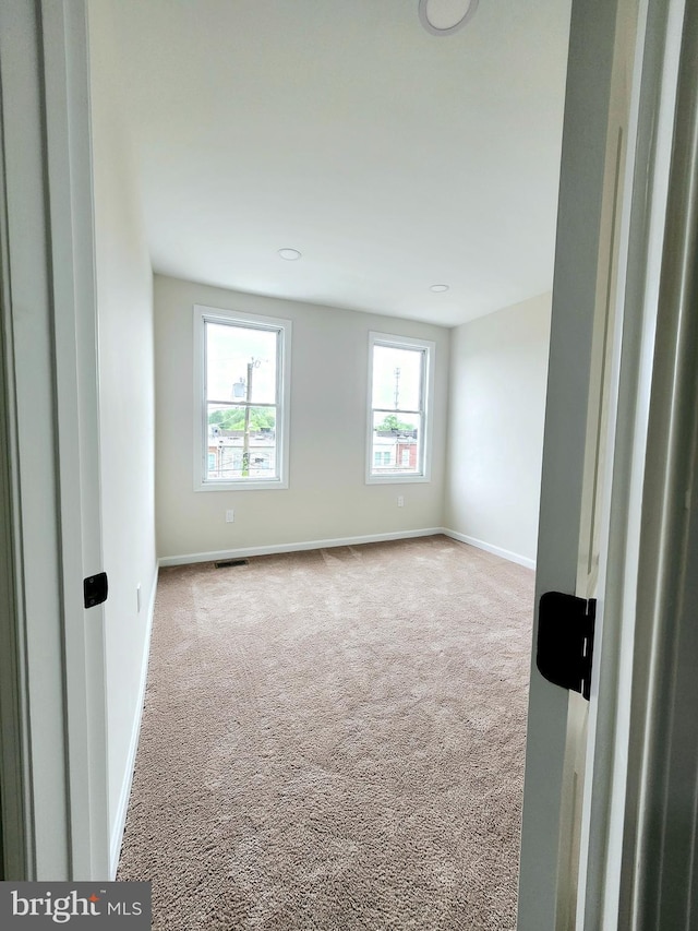 carpeted empty room featuring visible vents and baseboards