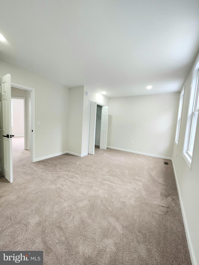 carpeted empty room featuring baseboards and visible vents