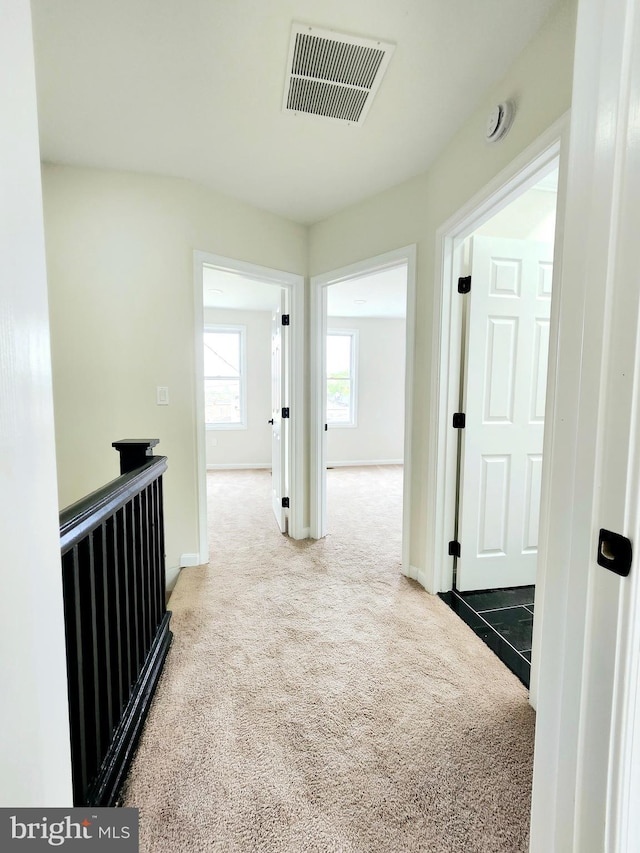 hallway with visible vents, baseboards, and carpet floors
