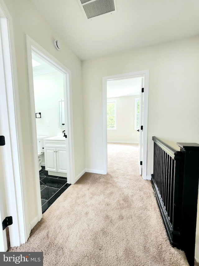 hall featuring carpet floors, baseboards, and visible vents
