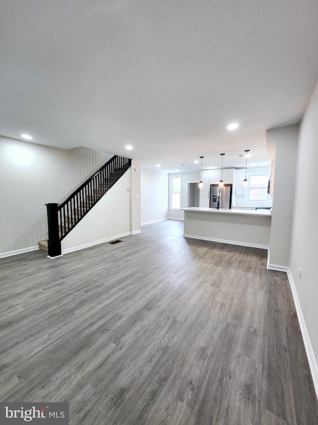 unfurnished living room with baseboards, visible vents, recessed lighting, and dark wood-type flooring