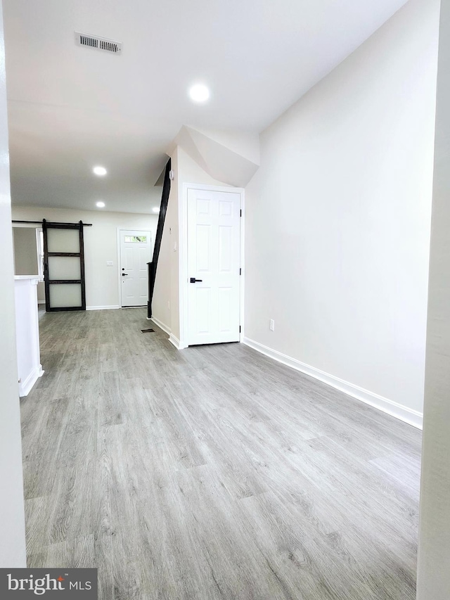interior space featuring wood finished floors, visible vents, a barn door, and baseboards