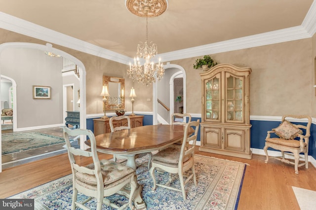 13457 Charolais Ct, Highland, MD 20777 - dining area featuring arched walkways, a chandelier, light wood finished floors, a wainscoted wall, and ornamental molding