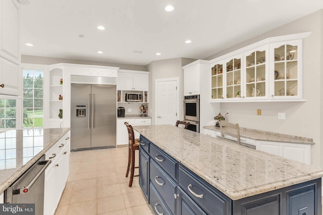 13457 Charolais Ct, Highland, MD 20777 - kitchen featuring appliances with stainless steel finishes, white cabinetry, a center island, recessed lighting, and glass insert cabinets
