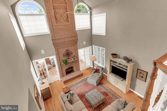 13457 Charolais Ct, Highland, MD 20777 - living room with a brick fireplace, a high ceiling, light wood-type flooring, and baseboards