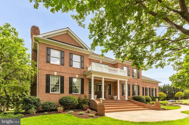 13457 Charolais Ct, Highland, MD 20777 - colonial-style house with a balcony, a chimney, brick siding, and a front lawn