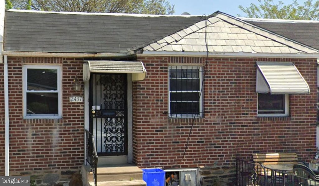 view of front of property featuring roof with shingles and brick siding
