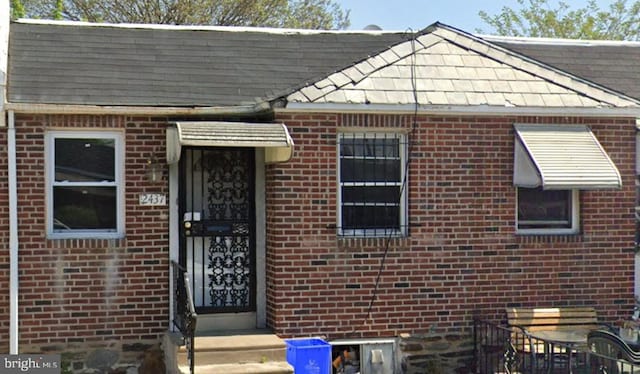 view of front of property featuring roof with shingles and brick siding
