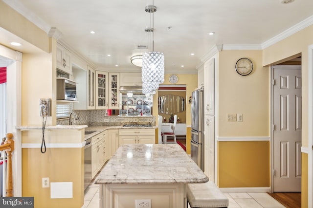 kitchen with glass insert cabinets, light stone counters, a kitchen island, backsplash, and appliances with stainless steel finishes