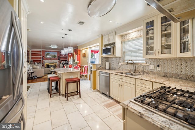 kitchen with visible vents, a sink, a kitchen bar, cream cabinetry, and stainless steel appliances